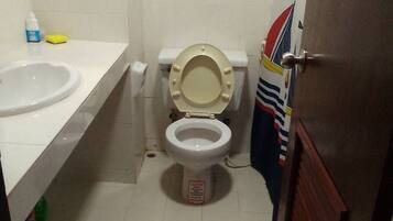 A small bathroom with a toilet, a sink, and a door.