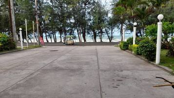 A paved pathway with a small cart, surrounded by trees and a view of the sea.