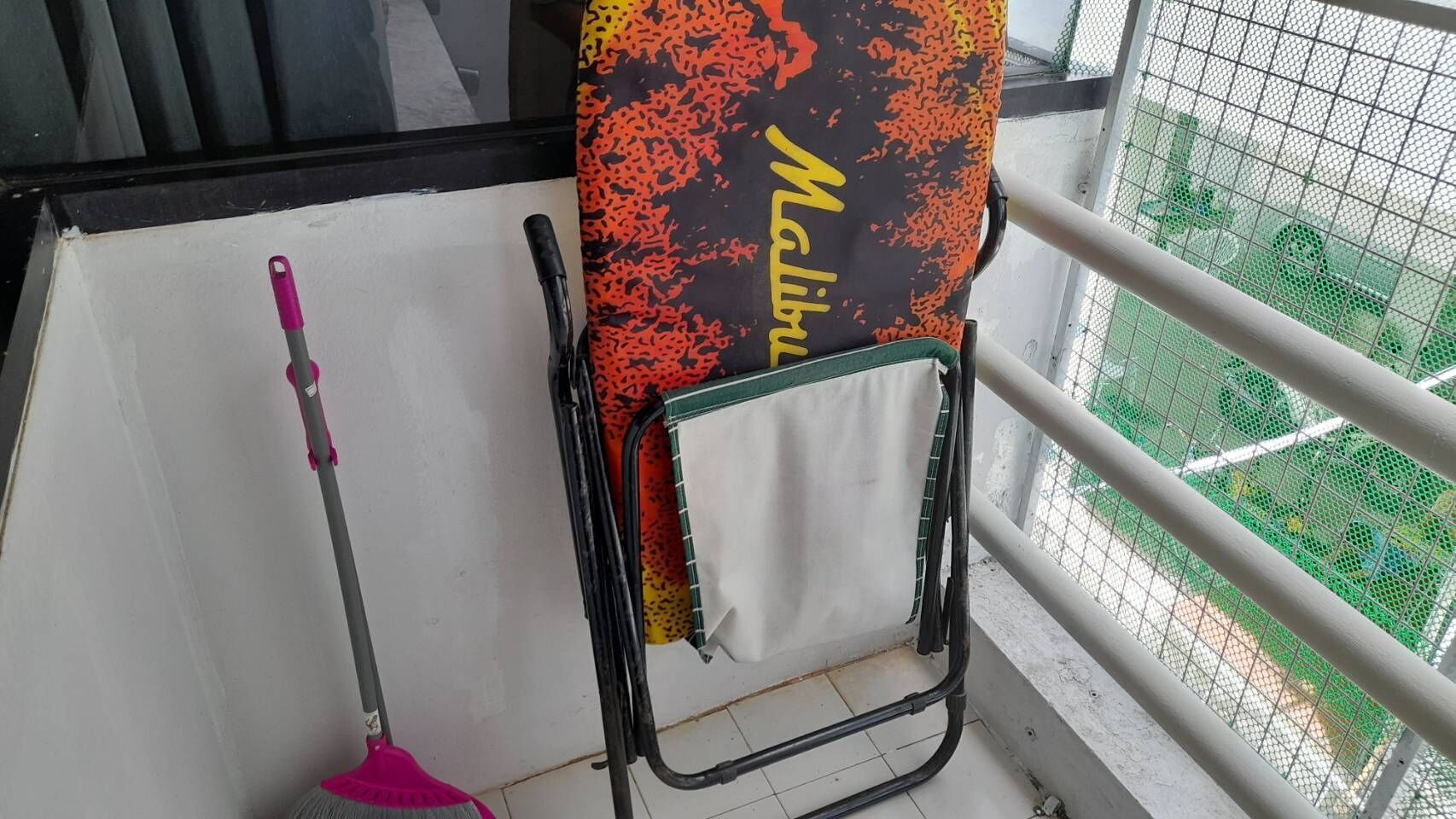 Una habitación con ventana, un trapeador y un tendedero con un paño estampado.