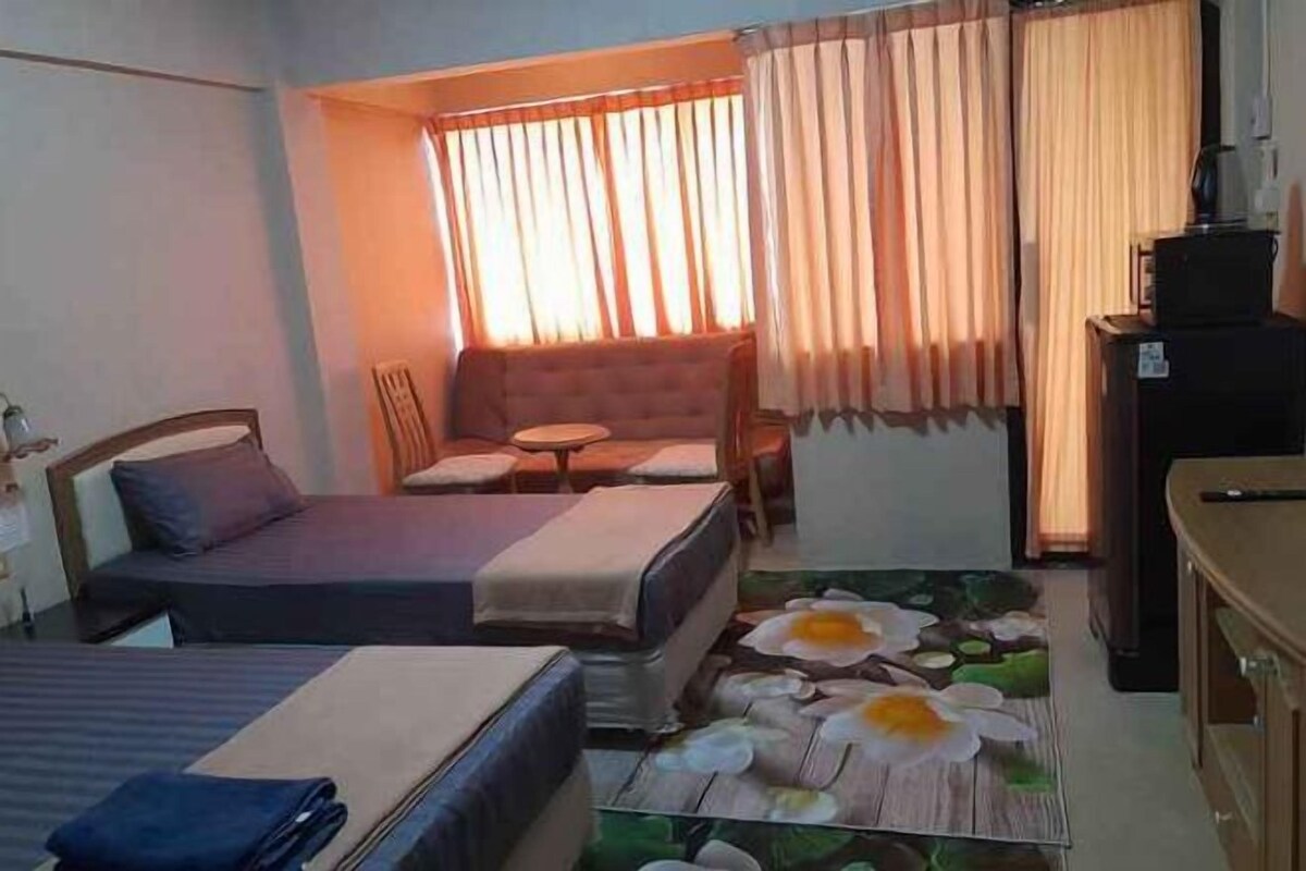 A hotel room with two beds, a sofa, a small table, and a TV.