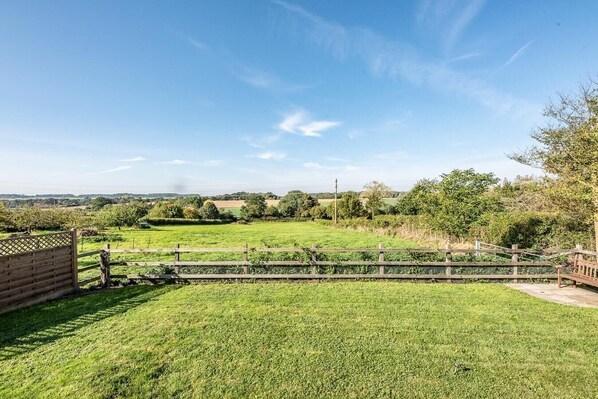 A grassy outdoor area with a wooden fence and a bench. - The Cabin, Parham (Parham)