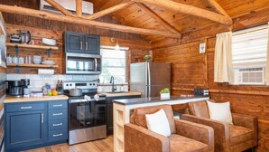 A cozy cabin-style kitchen with wooden walls, a central island, and a seating area with two sofas. - Rustic Cedar Waterfront Cabin 8 on Toledo Bend (Hemphill)
