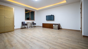 A spacious room with a wooden floor, a desk with chairs, a television, and a cabinet. - A1 Hotel (Mokpo)