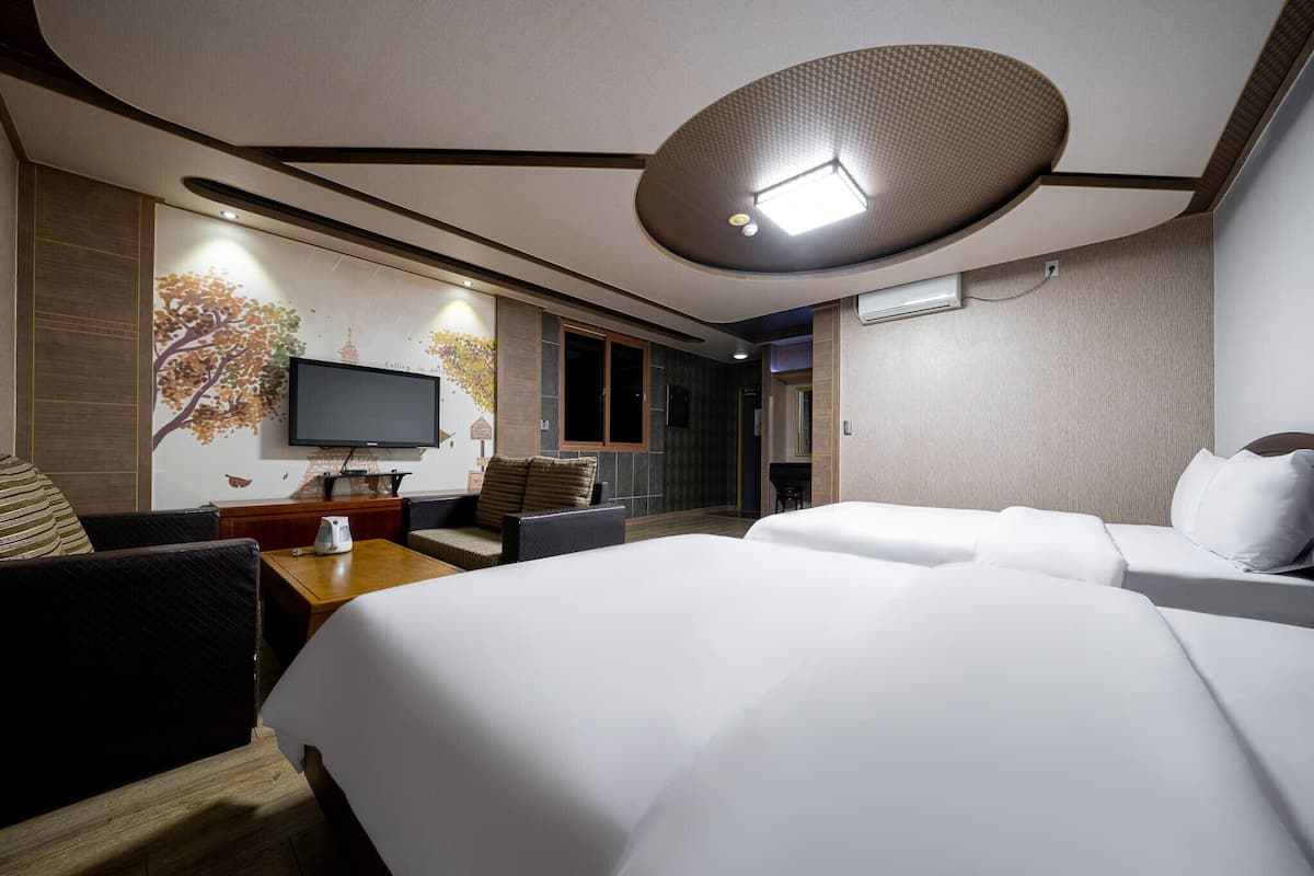 A hotel room with a large bed, a TV, a desk, and a seating area.