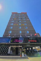 Un hotel de varios pisos con un cartel grande que dice 'Hotel' y un letrero de 'Estacionamiento' debajo.