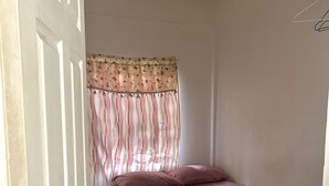 A bedroom with a bed, a door, and a curtain. - Tamernique Apartments (St. George's)