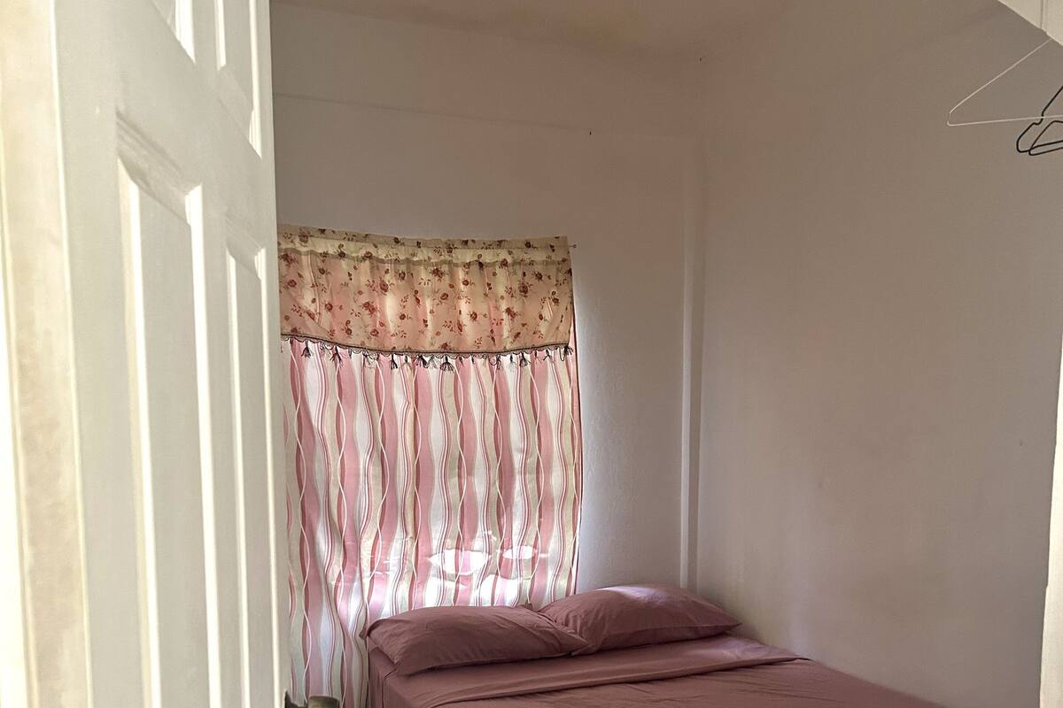 A bedroom with a bed, a door, and a curtain.