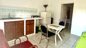 A compact kitchen with a sink, cabinets, and a dining area with a table and chairs. - Tamernique Apartments (St. George's)