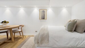 A minimalist bedroom with a bed, bedside table, and a framed picture on the wall. - Studio 221 on Bondi Beach (Bondi)