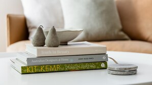 A stack of books on a white table with a bowl and decorative pears on top. - Studio 221 on Bondi Beach (Bondi)