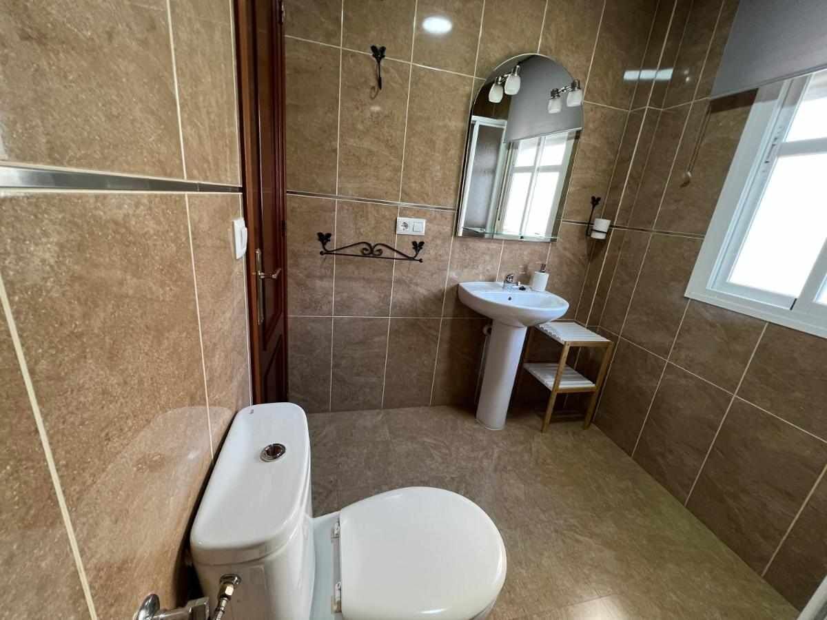 A bathroom with a toilet, sink, and mirror.