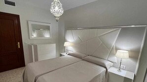 A bedroom with a large bed, two bedside tables with lamps, a mirror, and a chandelier. - AREVALO CENTER APARTMENT Free parking (Lucena)