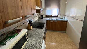 A compact kitchen with wooden cabinets, a granite countertop, and a built-in stove. - AREVALO CENTER APARTMENT Free parking (Lucena)