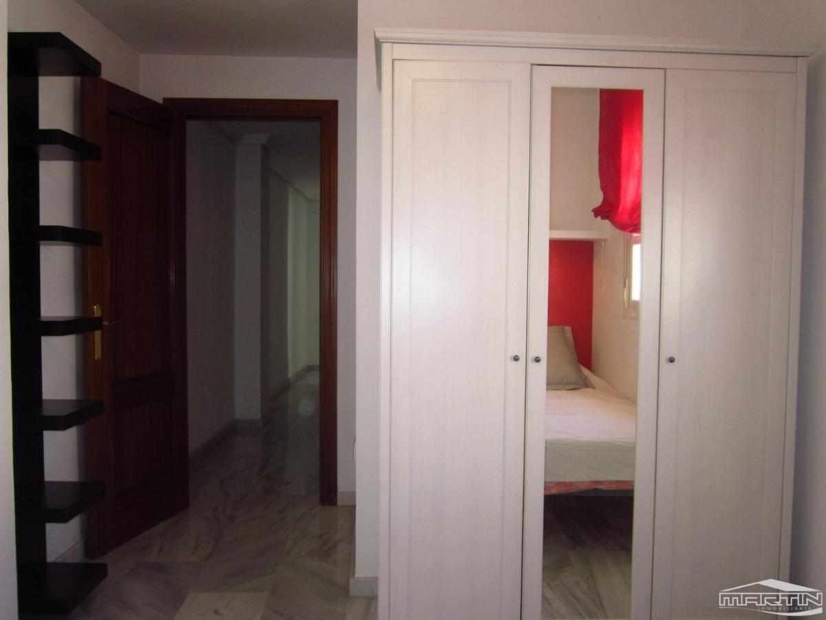 A room with a bed, a wardrobe, and a door leading to another room.