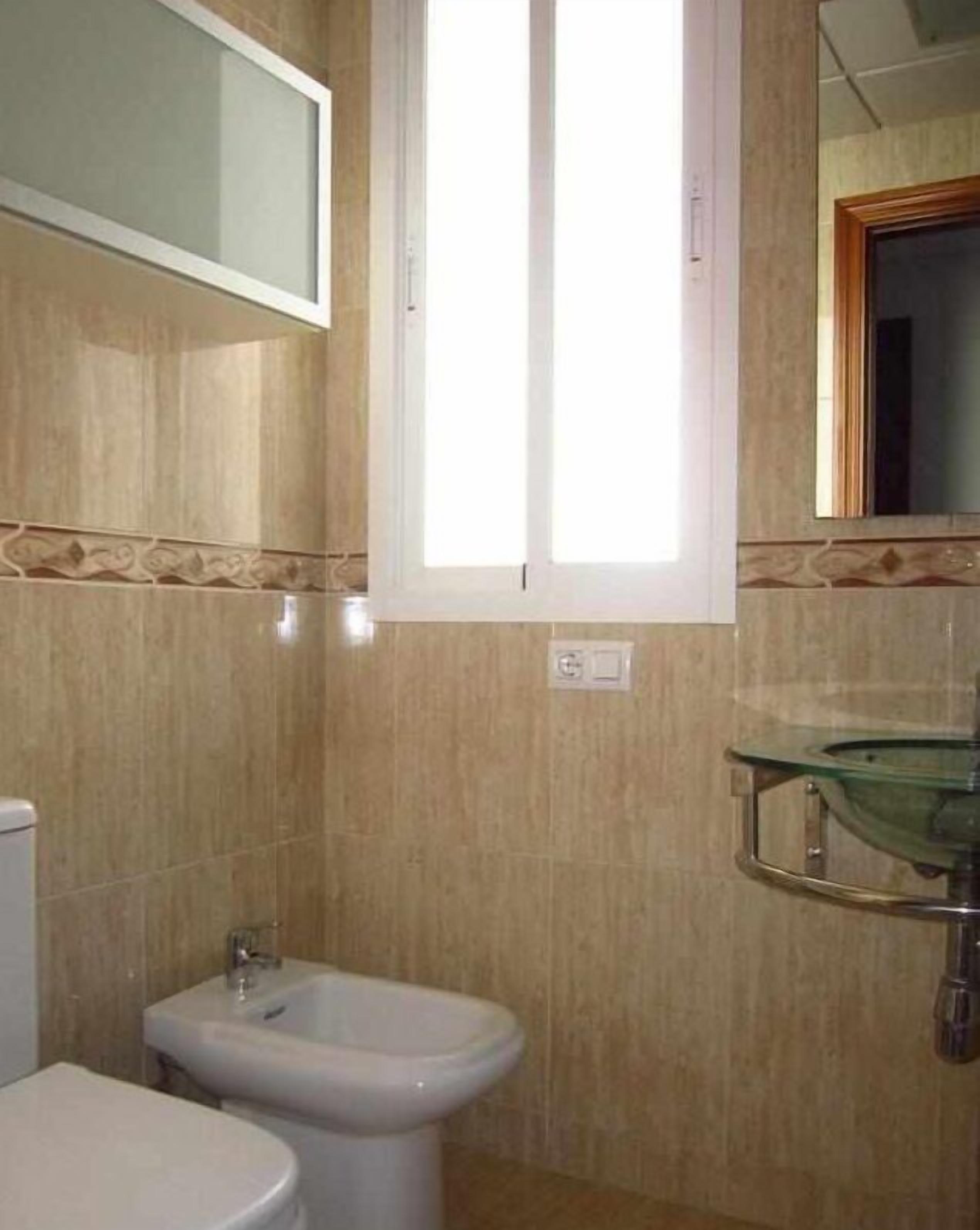 A bathroom with a bidet, toilet, and a glass sink.