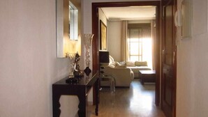 A hallway leading to a living room with a sofa and a lamp on a console table. - APARTMENT QUINTANA CENTER (Jauja)