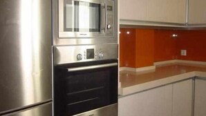 A compact kitchen with a built-in microwave and oven, stainless steel appliances, and a modern design. - APARTMENT QUINTANA CENTER (Jauja)