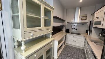 Une cuisine compacte avec des meubles blancs, une cuisinière encastrée et un crédence décorée.