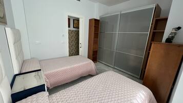 Un dormitorio con dos camas, un armario y una puerta que da a otra habitación.