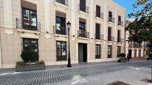 A building with multiple balconies, a paved courtyard, and a bench. - APARTMENT PALACIO DE LOS VIBORA (Lucena)