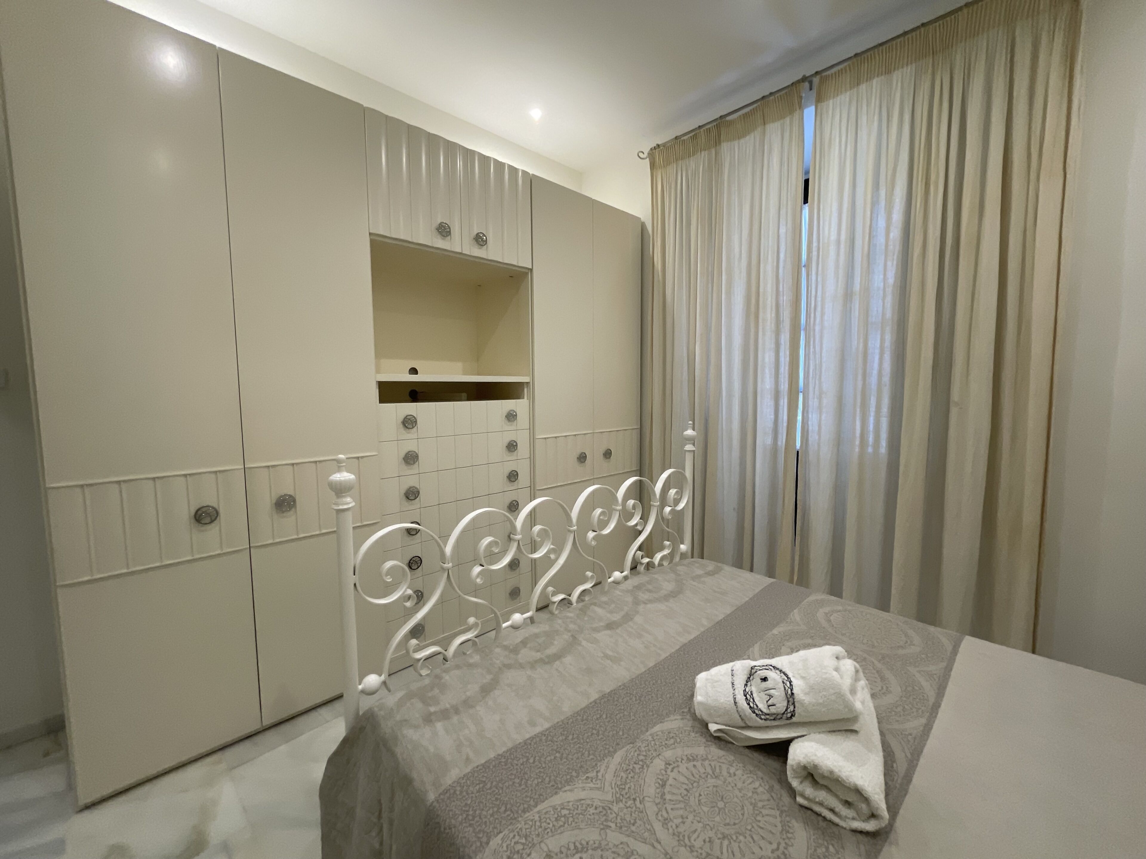 Une chambre à coucher avec un lit, une armoire et une fenêtre avec des rideaux.