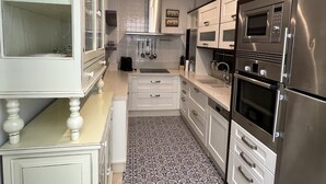 A modern kitchen with white cabinetry, stainless steel appliances, and patterned floor tiles. - APARTMENT PALACIO DE LOS VIBORA (Lucena)