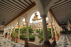 Une cour intérieure dotée d’arcades, de colonnes et d’une fontaine.