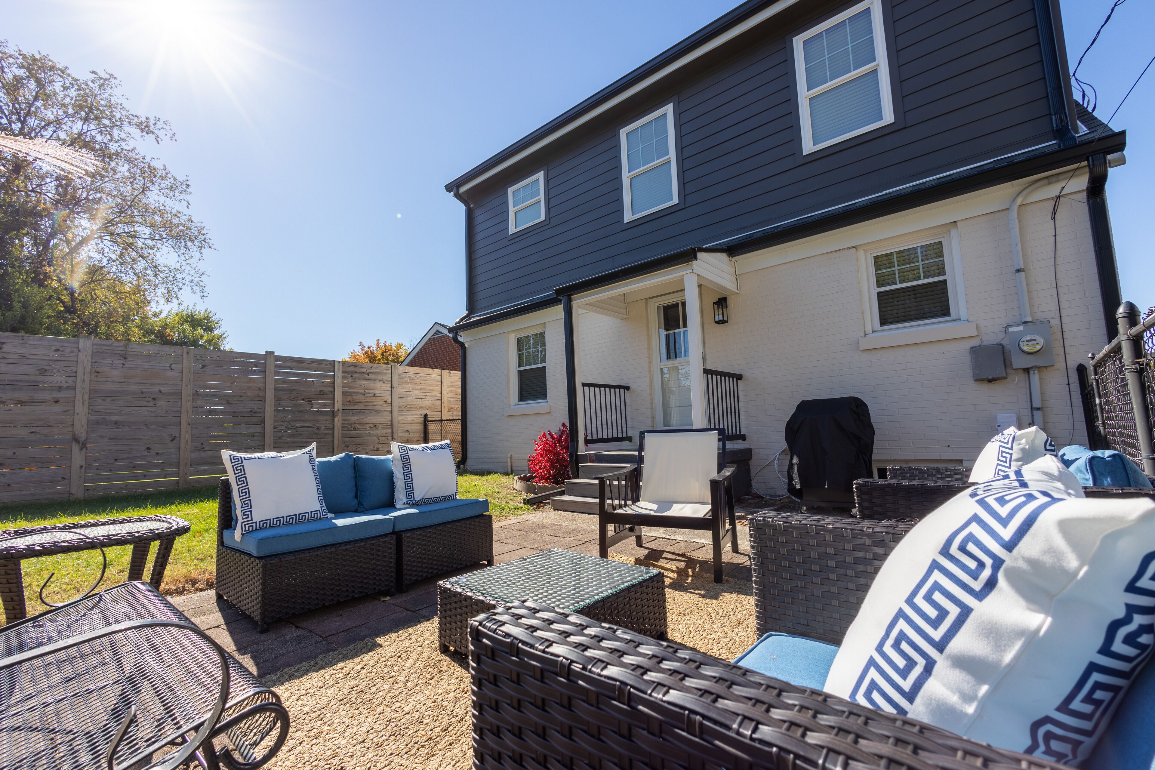 Une terrasse dotée de meubles en osier, d’un canapé bleu et d’un coussin décoratif blanc et bleu.
