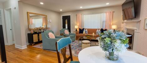 A spacious living room with a sofa, chairs, a dining table, and a fireplace.