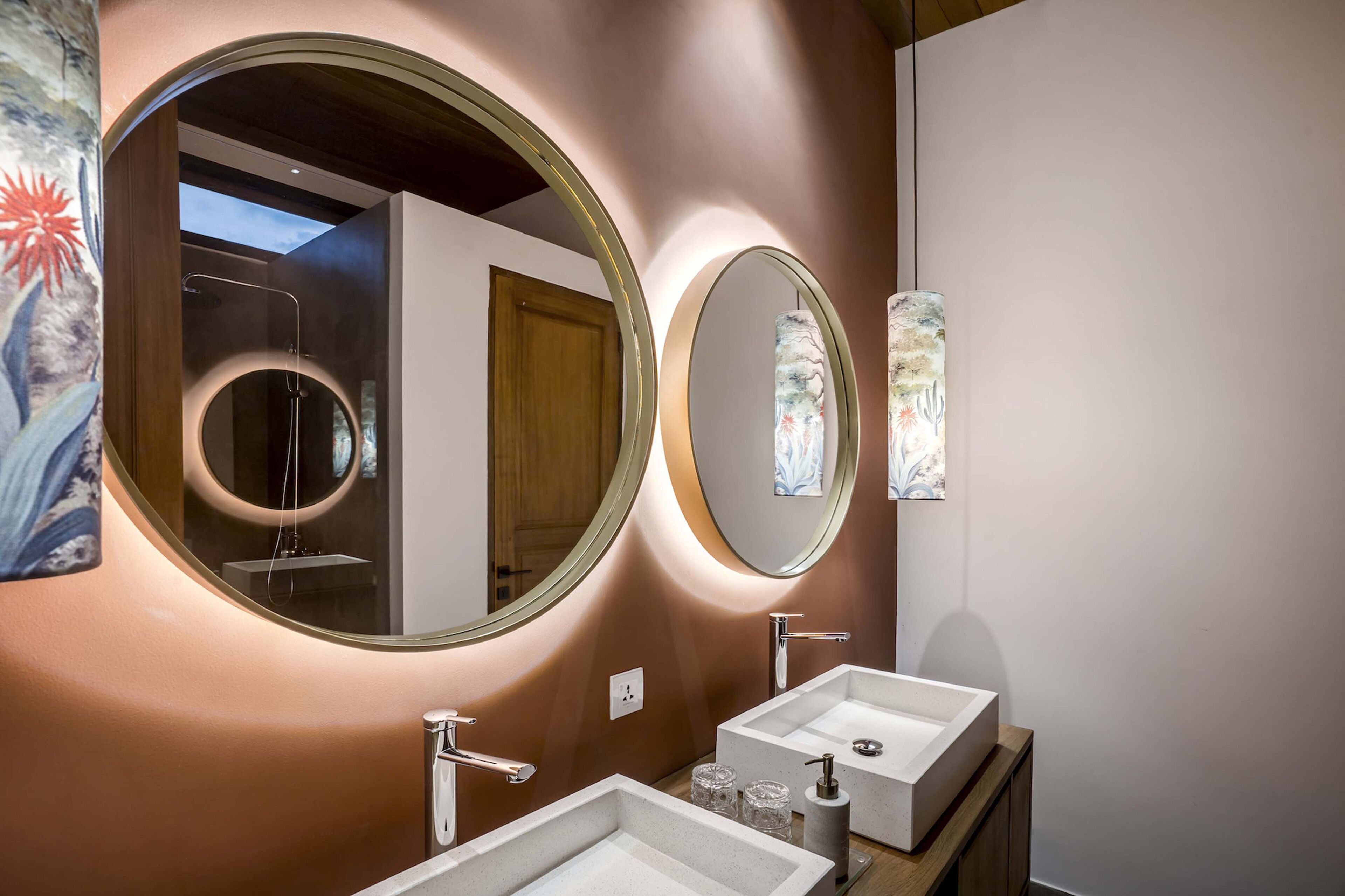 Ein modernes Badezimmer mit zwei Waschbecken, einem großen Spiegel und einer Wandleuchte.