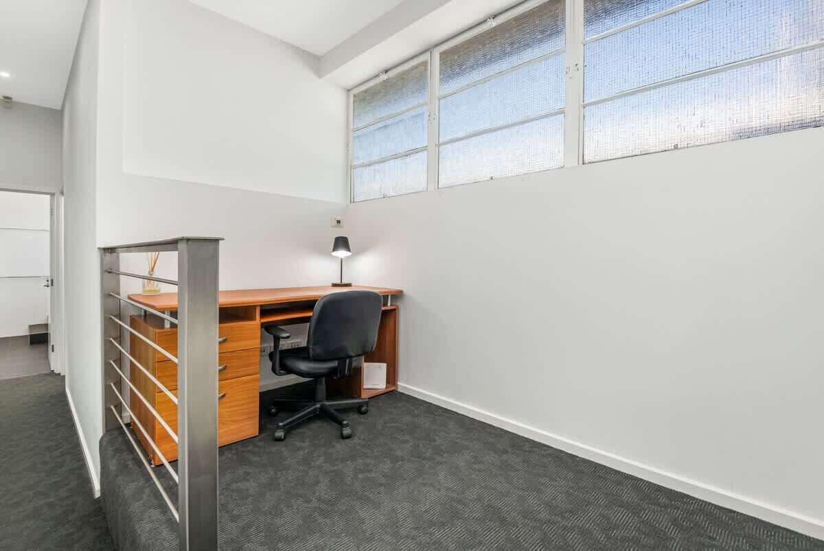A small office with a desk, chair, and a lamp.