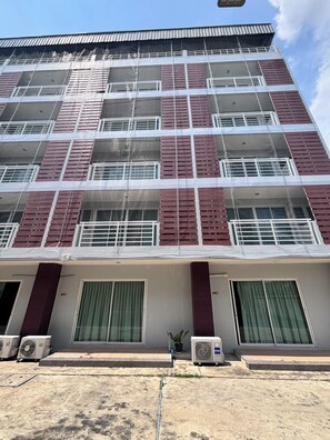 Un immeuble à plusieurs étages doté d’une façade symétrique, de grandes fenêtres et d’un toit plat.