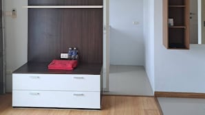 Een kamer met een wit kastje, een houten plank en een rode tas op de vloer.
