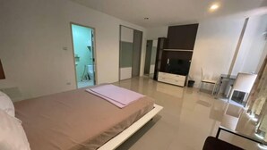 Een moderne slaapkamer met een groot bed, een televisie en een glazen scheidingswand.