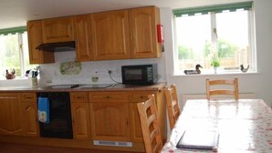 Une cuisine avec des meubles de rangement en bois, un four à micro-ondes et une table à manger avec des chaises.