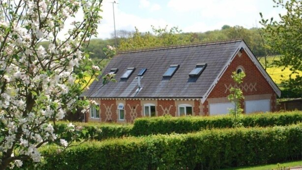Une maison en briques avec un toit en pente, de nombreuses fenêtres et un garage.