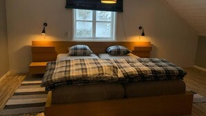 A bedroom with a bed, two bedside lamps, a window, and a wooden headboard. - Cozy swedish house with fireplace & big garden (Ramsele)