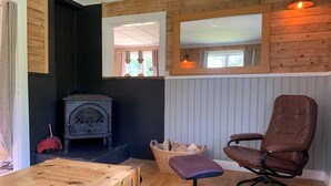 A cozy room with a wooden table, a brown leather chair, a wicker basket, and a vintage stove. - Cozy swedish house with fireplace & big garden (Ramsele)