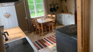 A compact kitchen with a dining table, chairs, a stove, and a window with curtains. - Cozy swedish house with fireplace & big garden (Ramsele)