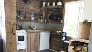 Una cucina rustica con mobili in legno, un frigorifero bianco e un piano cottura.
