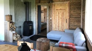 Un accogliente interno di una baita con arredamento in legno, un divano, un caminetto e un piccolo tavolo.