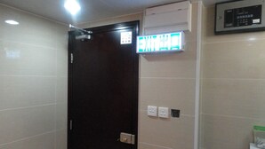 A hotel room with a closed door, an air conditioning unit, and a wall-mounted control panel. - Davao Hostel (Kowloon)