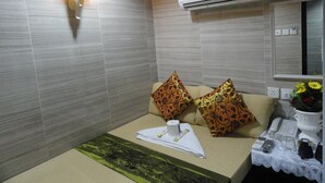 A hotel room with a bed, a bedside table with a telephone, a vase with flowers, and an air conditioning unit. - Davao Hostel (Kowloon)
