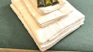 A stack of white towels on a green surface with three bottles of hair products on top. - Remarkable 5-Bed House in Horley (Horley)