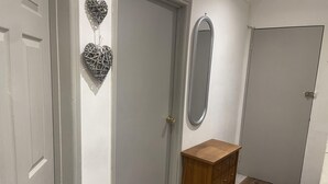 Un couloir avec une armoire en bois, un miroir et des objets décoratifs en forme de cœur accrochés au mur.