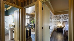A hallway leading to a bathroom with a sink and a dining area with chairs and a table.