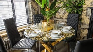A dining table set for six with black chairs, gold accents, and a vase with flowers.