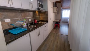 Cozinha moderna com armários brancos, micro-ondas e uma cadeira vermelha.