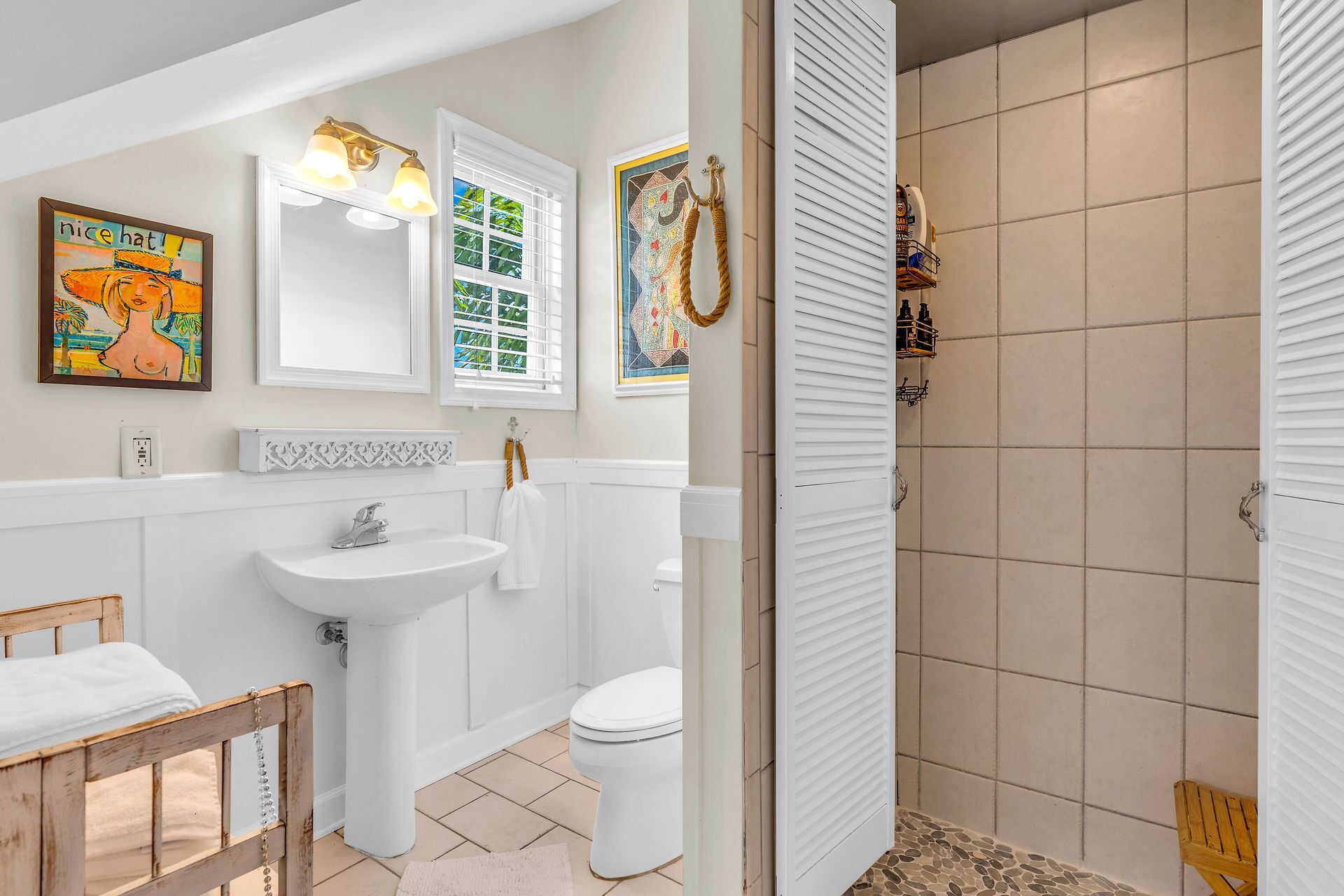 Une salle de bain avec un lavabo, des toilettes et un espace douche. Il y a un tableau au mur et un porte-serviettes.