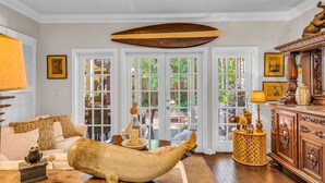 Un salón amplio con un gran barco de madera como pieza central, un sofá blanco y un mueble de madera decorado con objetos ornamentales.